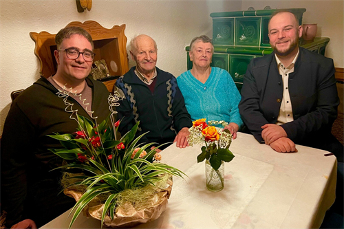 eine Gruppe von Menschen, die um einen Tisch mit Blumen sitzen